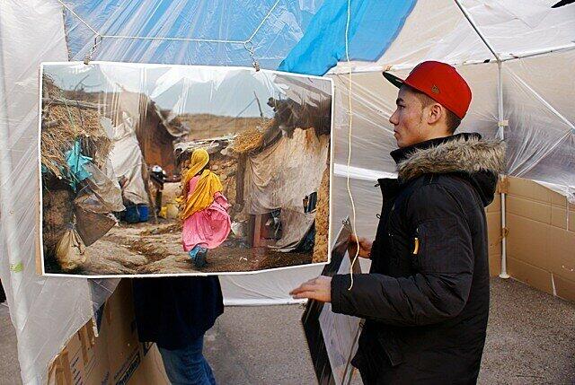 Ein junger Demonstrant vor einem Bild, das die erschütternde Realität in Afghanistan zeigt: Ein Mädchen in einem Notquartier.
