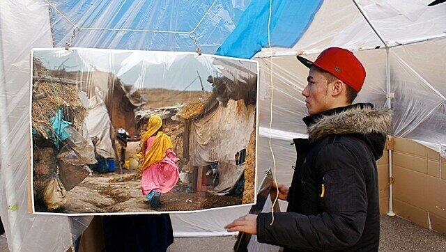 Ein junger Demonstrant vor einem Bild, das die erschütternde Realität in Afghanistan zeigt: Ein Mädchen in einem Notquartier. Ein junger Demonstrant vor einem Bild, das die erschütternde Realität in Afghanistan zeigt: Ein Mädchen in einem Notquartier.