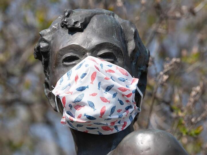 Eine selbstgebastelte Mundschutzmaske über der Kästner-Bronzeplastik in Dresden. Ingenieuren zufolge haben Staubsaugerbeutel für eine Maske der Marke Eigenbau hervorragende Filtereigenschaften.