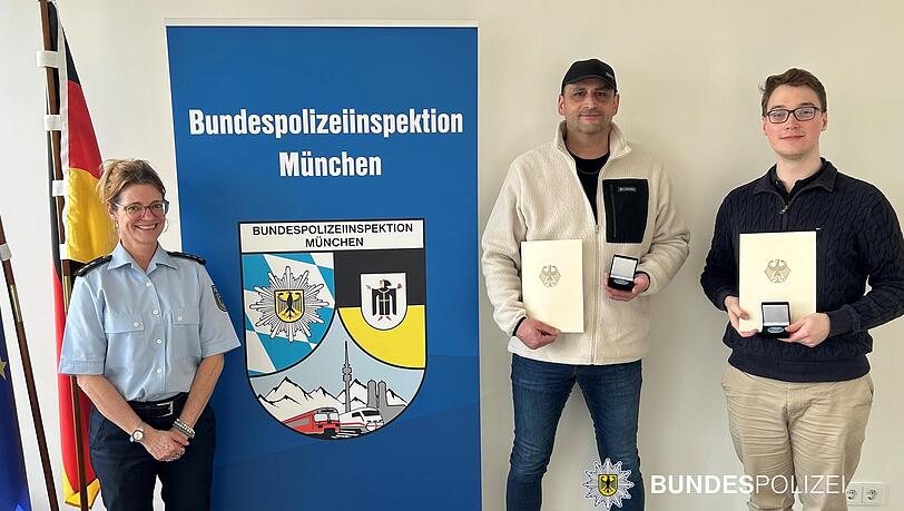 Die beiden geehrten Helfer. Links im Bild die stellvertretende Leiterin der Bundespolizeiinspektion M&uuml;nchen, Polizeidirektorin Sabine M&auml;der.