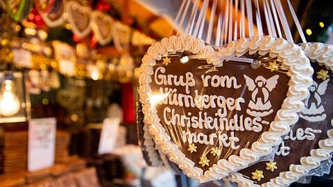 Lebkuchenherzen mit der Aufschrift "Gruß vom Nürnberger Christkindlesmarkt" hängen an einem Stand. Foto: Daniel Karmann