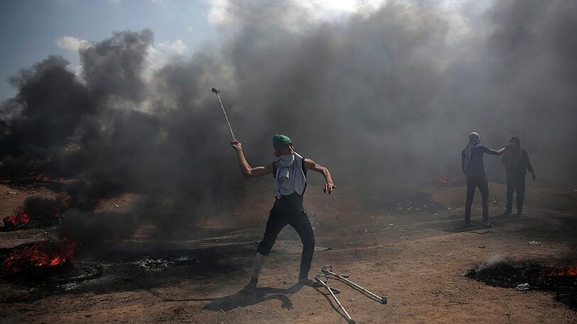Palästinenser schleudern Steine gegen israelischen Truppen bei den Protesten für die Rückkehr in ihre Heimat anlässlich des Nakba-Tags.