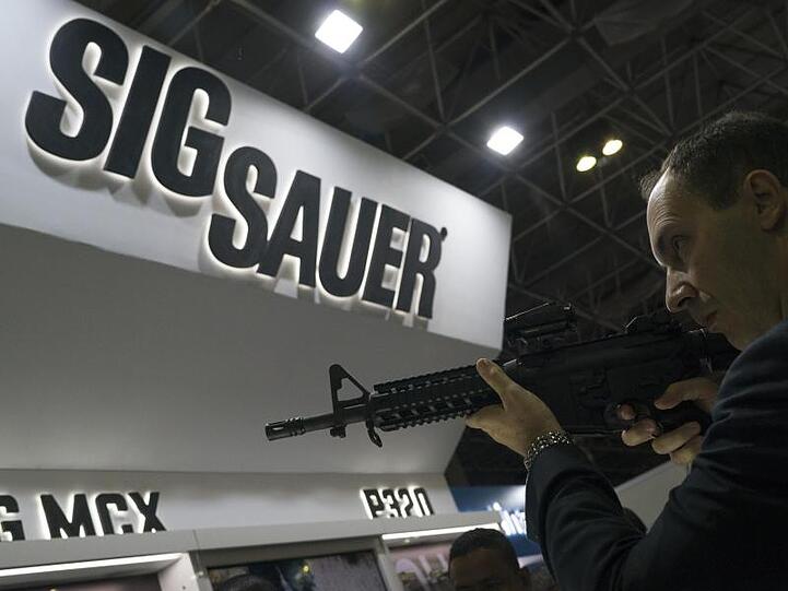 Ein Mann testet auf einer Waffenmesse ein Sig-Sauer-Gewehr.