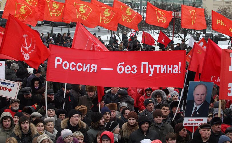 Während der Pro-Putin Demo, versammelten sich Tausende,um gegen den Kremlkandidaten zu protestieren. Anhänger der Oppositionspartei "Kommunistische Partei der Russischen Föderation" (KPRF) hielten Banner mit "Russia - without Putin" hoch oder stellten Putin als Adolf Hitler dar.