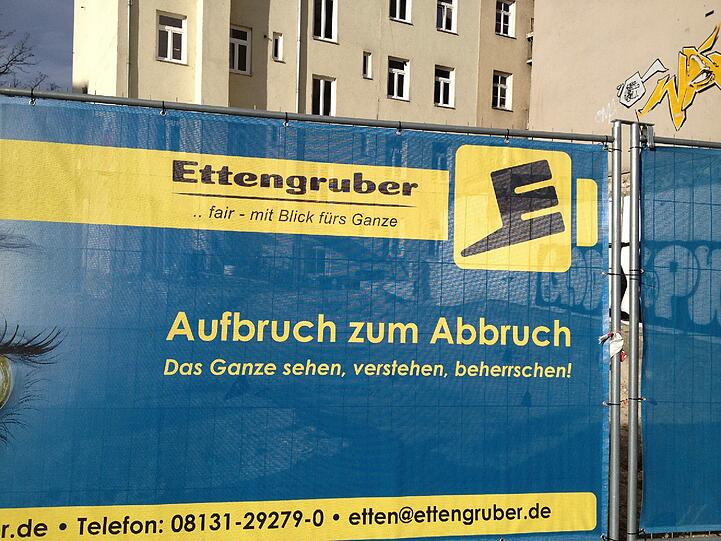Vom "Blick aufs Ganze" - wie es das Abbruchunternehmen auf seinem Transparent verspricht - werden die alteingesessenen Bewohner der Häuser hinter den Glockenbachsuiten in Zukunft wohl nur träumen können....