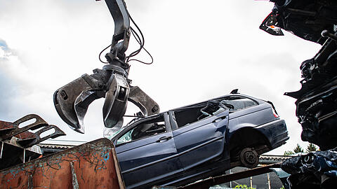 Ein Autowrack wird bei einem Recyclingbetrieb, mit dem Greifarm eines Baggers in die Schrottpresse verfrachtet. (Symbolbild) Ein Autowrack wird bei einem Recyclingbetrieb, mit dem Greifarm eines Baggers in die Schrottpresse verfrachtet. (Symbolbild)