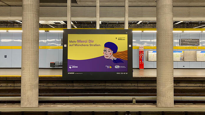 Ein Infoscreen mit einem "Merci dir"-Motiv am U-Bahnhof Max-Weber-Platz.