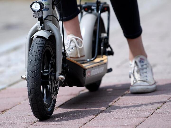 Eine Frau macht auf einem E-Scooter "Metz Moover" vor dem Geschäft von efuture eine Probefahrt.