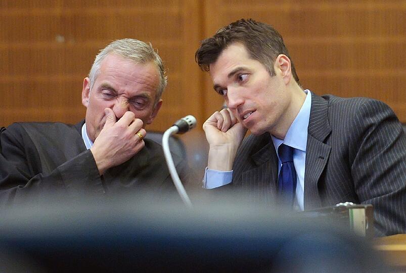 Der Anwalt Daniel M. Krause (l) und der angeklagte Ex-Börsenguru Markus Frick besprechen sich während der Verhandlungspause vor der Urteilsverkündung am 25.02.2014 im Gerichtssaal vor der 28. Strafkammer des Landgerichts Frankfurt