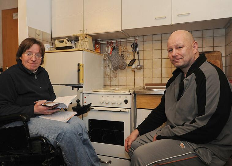 Schwester Mirjam Ullmann und Michael B. vor der Kochnische im Wohnzimmer. Der Kühlschrank ist kaputt, der Herd ebenso.