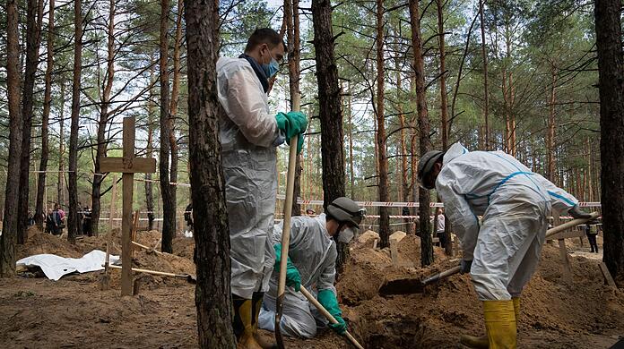 Arbeiter stehen auf dem Waldfriedhof von Isjum am Grab eines nicht identifizierten Zivilisten. Dort wurden nach Angaben aus Kiew mehr als 400 Leichen gefunden. Die Menschen sollen ums Leben gekommen sein, als Russland die Stadt Ende März beschoss.