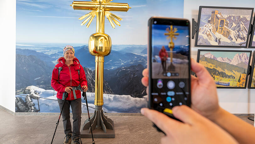Selfie auf sicherer Position und immer mit gutem Wetter. Im richtigen Winkel sieht es echt aus. Eine Wanderin lässt sich am Vormittag vor dem 2. Gipfelkreuz auf der Zugspitze fotografieren, das ab dem 3. Juli in der Ausstellung in den Innenräumen der Gipfelstation auf der Zugspitze aufgestellt ist. Der Nachbau soll es den Besuchern ermöglichen, das Gipfelkreuz ganz ohne risikoreiche Kletterei zu besuchen und sich darauf verewigen zu können.