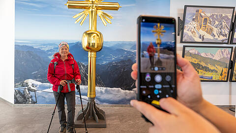 Selfie auf sicherer Position und immer mit gutem Wetter. Im richtigen Winkel sieht es echt aus. Eine Wanderin lässt sich am Vormittag vor dem 2. Gipfelkreuz auf der Zugspitze fotografieren, das ab dem 3. Juli in der Ausstellung in den Innenräumen der Gipfelstation auf der Zugspitze aufgestellt ist. Der Nachbau soll es den Besuchern ermöglichen, das Gipfelkreuz ganz ohne risikoreiche Kletterei zu besuchen und sich darauf verewigen zu können.
