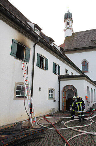 Einsatzkräfte der Feuerwehr stehen am Sonntagmorgen vor dem Franziskanerkloster in Füssen.