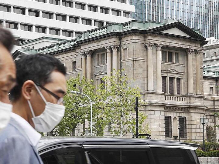 Menschen gehen mit Gesichtsmasken am Gebäude des Hauptsitzes der "Bank of Japan" (BoJ) in Tokio vorbei.
