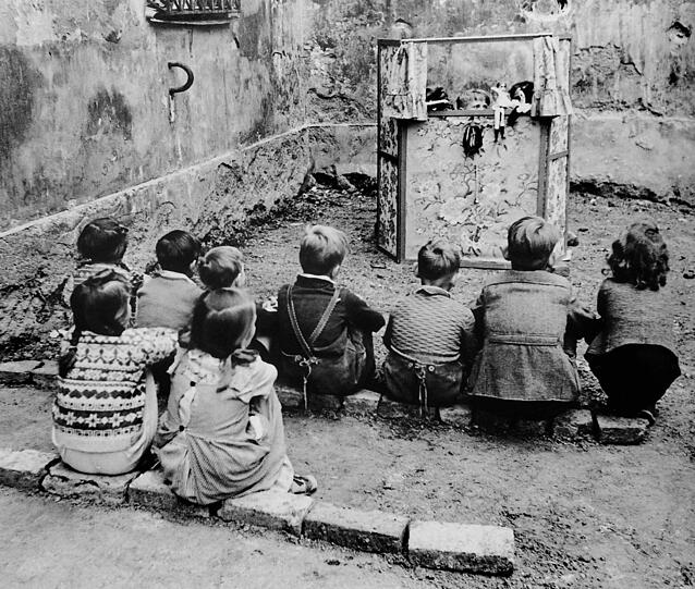1952: Kinder spielen Kasperltheater, zum Sitzen für die Zuschauer tun's auch Ziegelsteine.