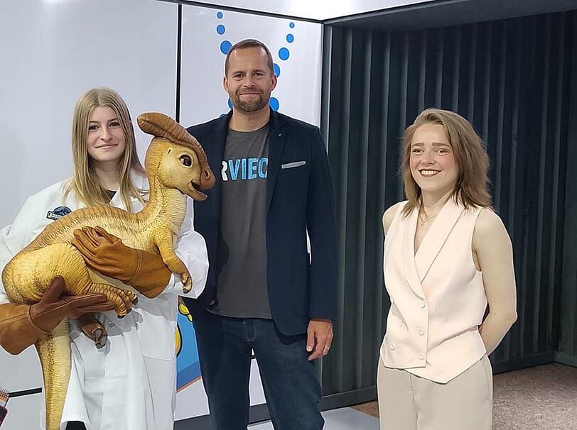 Peter Kapustin und  Assistenz der Ausstellungsleitung Vivien zusammen mit dem Dino-Baby.