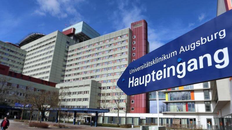 Ein Schild weist zum Eingang des Universitätsklinikums Augsburg. Foto: Karl-Josef Hildenbrand/dpa/Archivbild