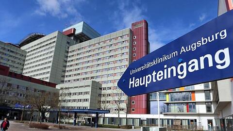 Ein Schild weist zum Eingang des Universitätsklinikums Augsburg. Foto: Karl-Josef Hildenbrand/dpa/Archivbild