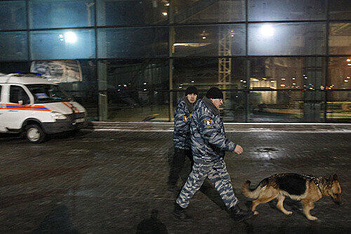 Russische Polizeibeamte mit einem Spürhund am Flughafen.