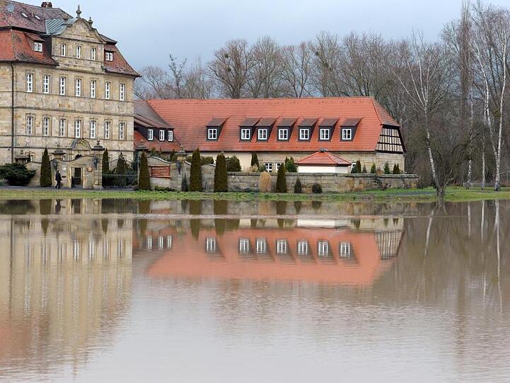 Die Seniorenresidenz Schloss Gleusdorf spiegelt sich in einer überfluteten Wiese. Foto: David-Wolfgang Ebener/Archivbild