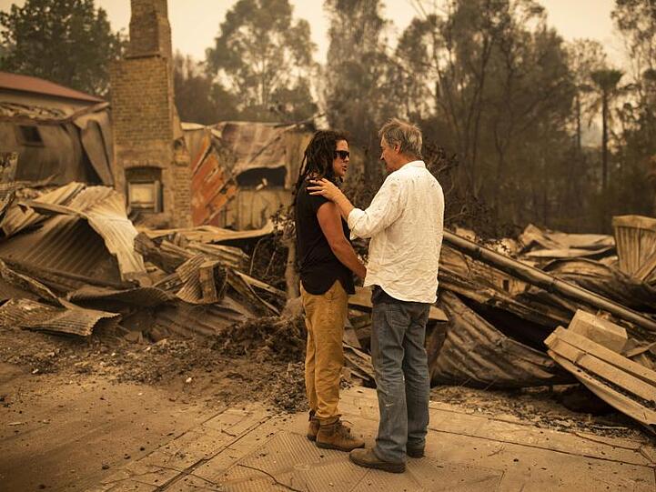 Geschäftsinhaberin Sally Anne Wilson (l.) und ihr Partner Christopher Lee stehen vor ihrem durch Buschfeuer zerstörten Laden im Bundesstaat New South Wales.