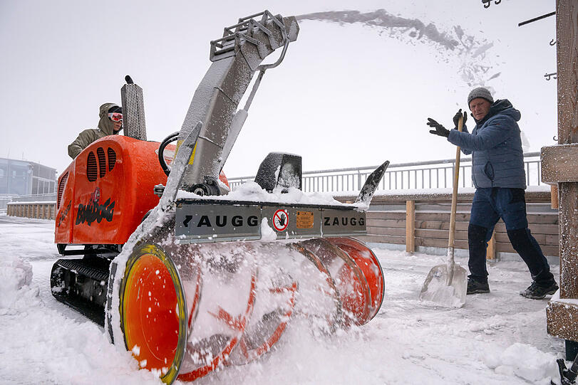 Eine Frau und ein Mann räumen den Neuschnee auf der Aufsichtsplattform der Zugspitze.