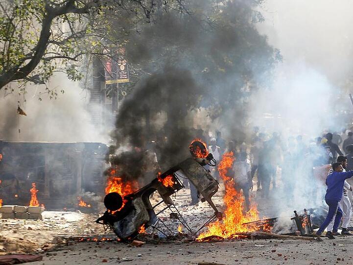 Demonstranten zünden ein Fahrzeug in Neu Delhi an.