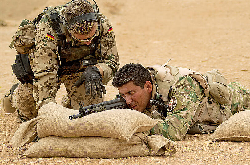 Ein Bundeswehrsoldat weist einen kurdischen Peschmerga in die Handhabung des G3-Sturmgewehrs in Erbil ein.