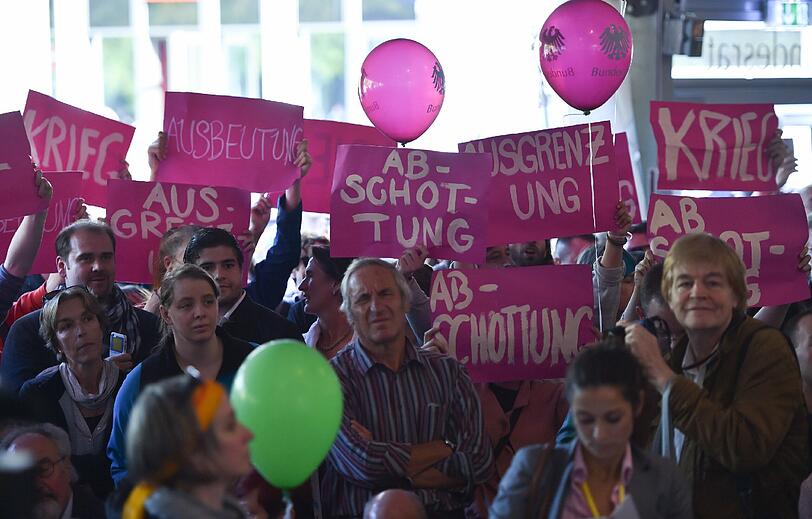 Demonstranten halten am 03.10.2015 bei der symbolischen Amtsübergabe im Bundesratszelt der Einheitsfeier in Frankfurt am Main (Hessen) Plakate mit den Worten "Krieg", "Ausbeutung", "Abschottung" und "Ausgrenzung" hoch.