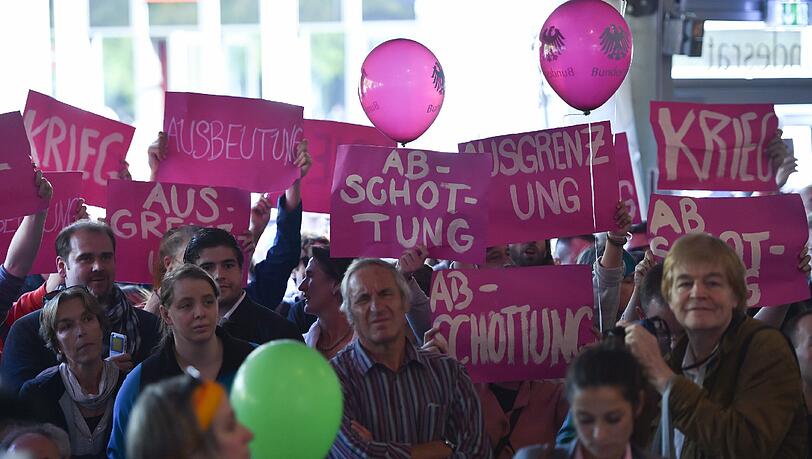 Demonstranten halten am 03.10.2015 bei der symbolischen Amtsübergabe im Bundesratszelt der Einheitsfeier in Frankfurt am Main (Hessen) Plakate mit den Worten "Krieg", "Ausbeutung", "Abschottung" und "Ausgrenzung" hoch. Demonstranten halten am 03.10.2015 bei der symbolischen Amtsübergabe im Bundesratszelt der Einheitsfeier in Frankfurt am Main (Hessen) Plakate mit den Worten "Krieg", "Ausbeutung", "Abschottung" und "Ausgrenzung" hoch.