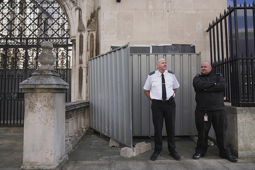 Sicherheitsbeamte stehen vor dem Royal Courts of Justice vor großen schwarzen Plastikfolien und zwei Metallbarrieren, hinter denen sich das neueste Kunstwerk des Straßenkünstlers Banksy verbirgt.
