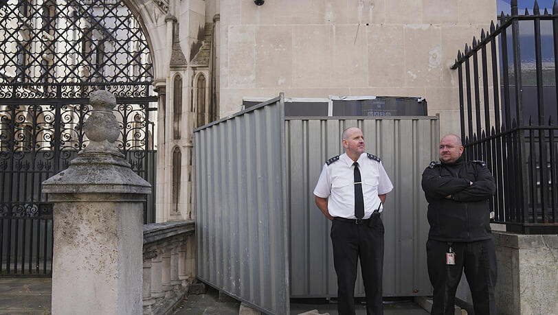 Sicherheitsbeamte stehen vor dem Royal Courts of Justice vor großen schwarzen Plastikfolien und zwei Metallbarrieren, hinter denen sich das neueste Kunstwerk des Straßenkünstlers Banksy verbirgt. Sicherheitsbeamte stehen vor dem Royal Courts of Justice vor großen schwarzen Plastikfolien und zwei Metallbarrieren, hinter denen sich das neueste Kunstwerk des Straßenkünstlers Banksy verbirgt.