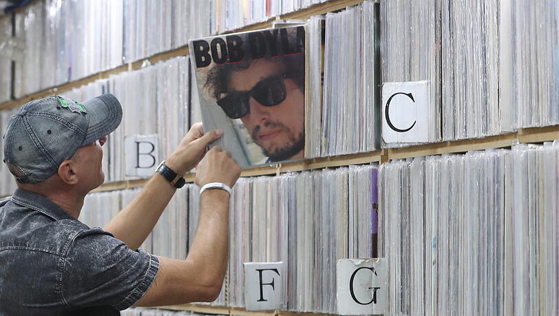 Ein Kunde zieht ein Album des US-amerikanischen Singer-Songwriters Bob Dylan in einem Plattenladen.