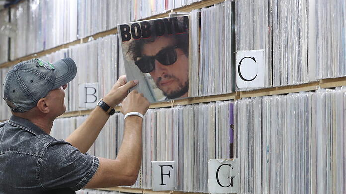 Ein Kunde zieht ein Album des US-amerikanischen Singer-Songwriters Bob Dylan in einem Plattenladen.