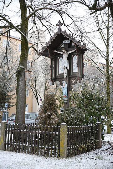 Ein Marterl auf einer kleinen Wiese am Straßenrand.