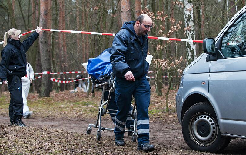 Mitarbeiter der Gerichtsmedizin bringen in einem Waldstück an der Bärenlauchstraße eine Leiche zu ihrem Fahrzeug.