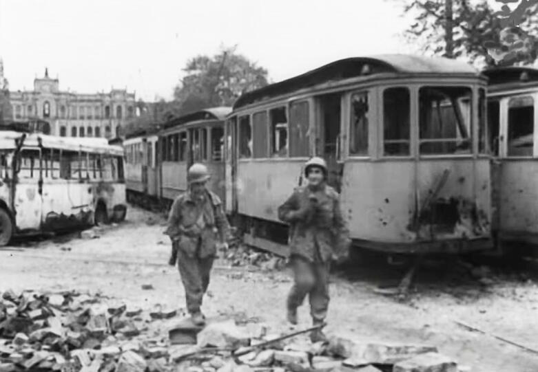 1945: Zerstörte Straßenbahnen auf der Maximiliansbrücke. Im Hintergrund das teilweise ausgebrannte Maximilianeum.