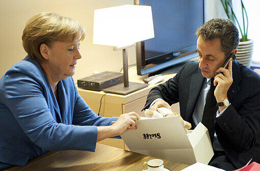 Baby-Geschenk: Angela Merkel überreicht Sarkozy hinter den Kulissen einen Teddybären für die kleine Giulia.