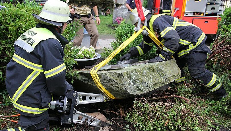 Feuerwehrmänner heben den umgefallenen Grabstein am Memminger Waldfriedhof mit einem Hydraulikspreizer hoch. Feuerwehrmänner heben den umgefallenen Grabstein am Memminger Waldfriedhof mit einem Hydraulikspreizer hoch.