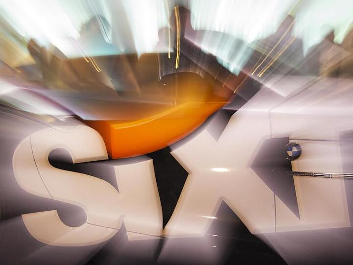 Das Sixt-Logo ist vor einem Sportwagen zu sehen. Foto: picture alliance / dpa/Symbolbild