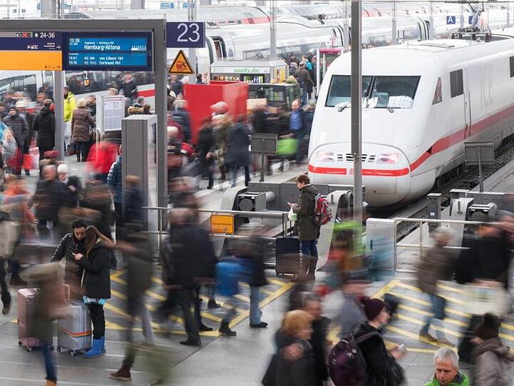Reisende gehen am Hauptbahnhof über eine Plattform.