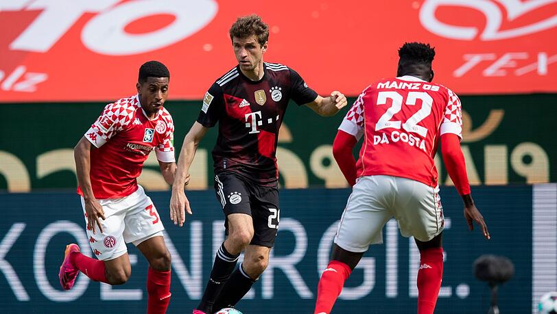Bayern Münchens Thomas Müller (M) in Aktion gegen die Mainzer Leandro Barreiro Martins (l) Danny Vieira da Costa.
