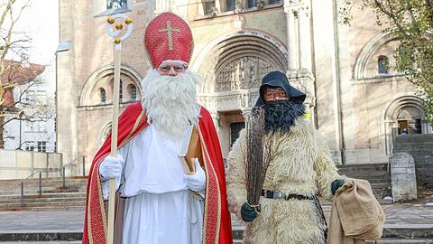 So und nicht anders schaut er aus, der wahrhaftige bayerische Nikolaus: Er trägt eine rote Mitra auf dem Kopf, ein Bischofsornat mit weißem Chorgewand darunter, einen Bischofsstab und ein Goldenes Buch. Hier zu sehen ist der Münchner Nikolaus Martin Bayerl, zusammen mit seinem Sohn Kilian, der ihn als Krampus begleitet. Im Hintergrund die katholische St.-Anna-Kirche im Lehel.