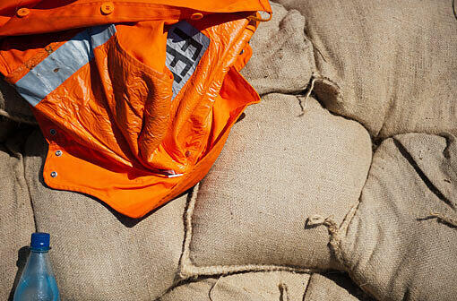 Eine orange Feuerwehrjacke liegt samt Wasserflasche am 07.06.2013 in Damnatz (Niedersachsen) auf dem Elbdeich auf Sandsäcken