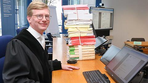 Richter Maximilian Kuhn mit E-Akte auf dem Monitor und dem "Gürteltier" daneben.