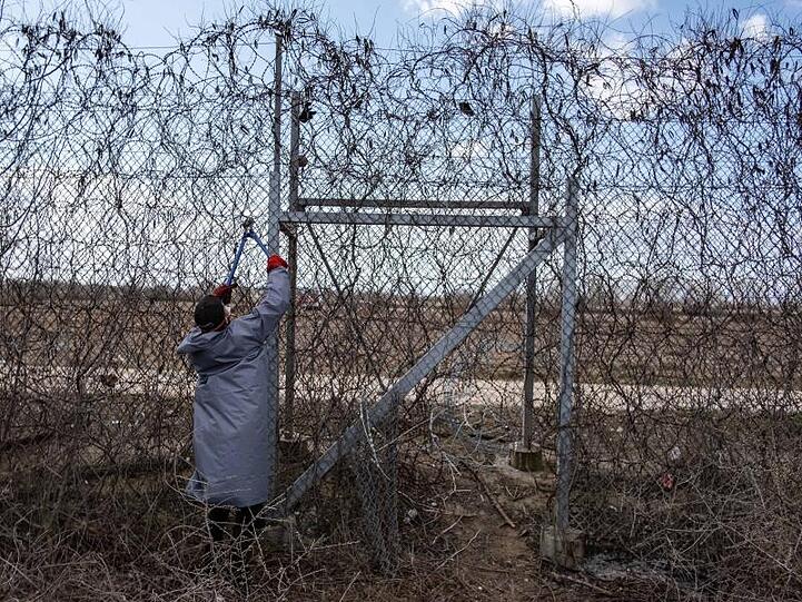 Ein Migrant versucht an der türkisch-griechischen Grenze, mit einer Drahtschere den Zaun durchzuschneiden.