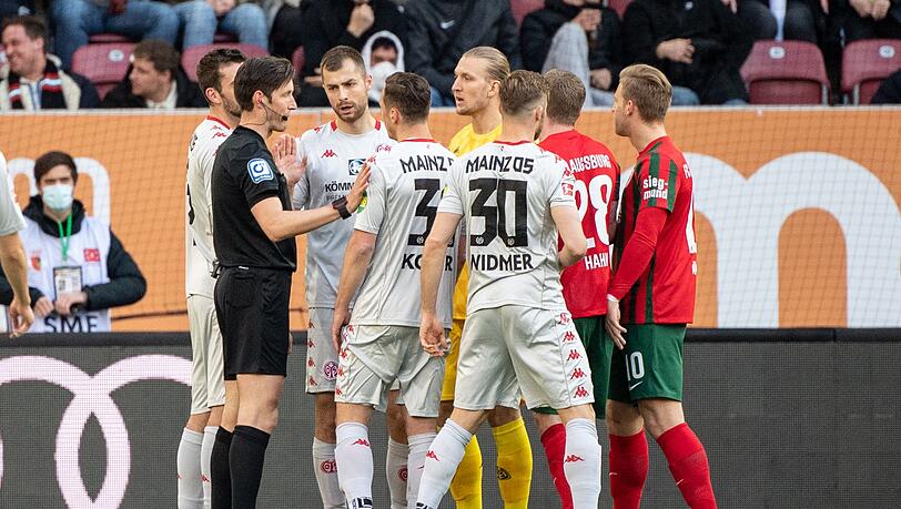 Die Spieler von Mainz diskutieren mit Schiedsrichter Matthias Jöllenbeck (l).