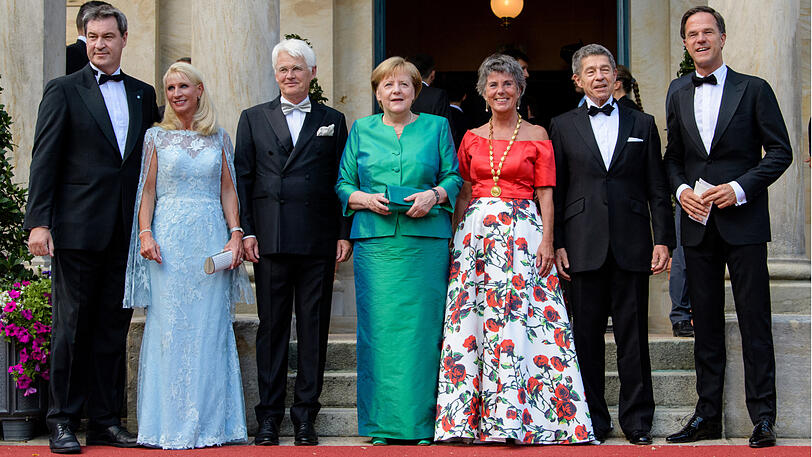 Markus Söder (CSU, l.-r.), Ministerpräsident von Bayern, seine Frau Karin, Thomas Erbe, Mann der Bürgermeisterin von Bayreuth, Angela Merkel (CDU), Bundeskanzlerin, Brigitte Merk-Erbe, Bürgermeisterin von Bayreuth, Joachim Sauer, Mann von Kanzlerin Merkel, und Marc Rutte, Ministerpräsident der Niederlande, stehen vor dem Festspielhaus.