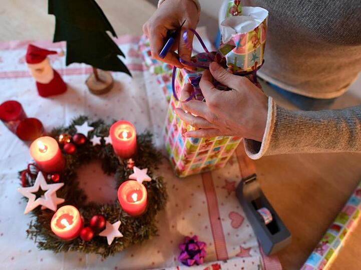 Eine Frau packt am vierten Advent Weihnachtsgeschenke ein.